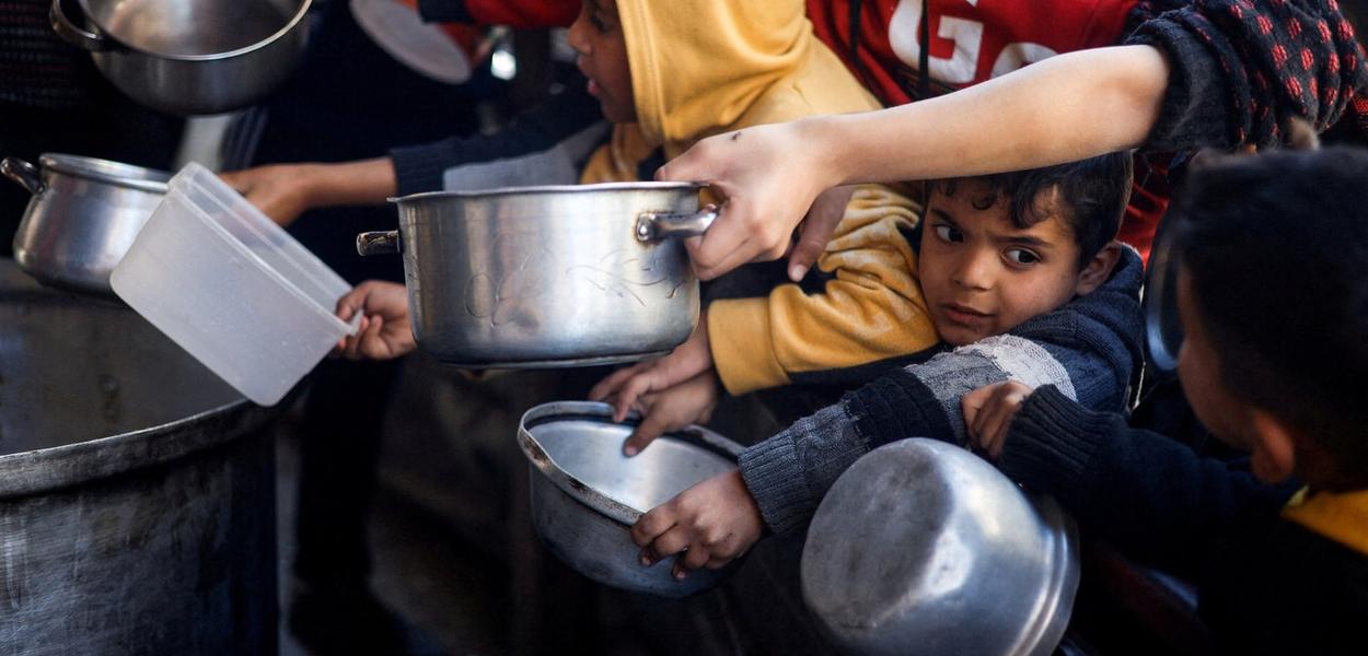 Crianças palestinas aguardam para receber comida de uma cozinha de caridade em meio à escassez de suprimentos, em Rafah, sul da Faixa de Gaza
05/03/2024
REUTERS/Mohammed Salem
