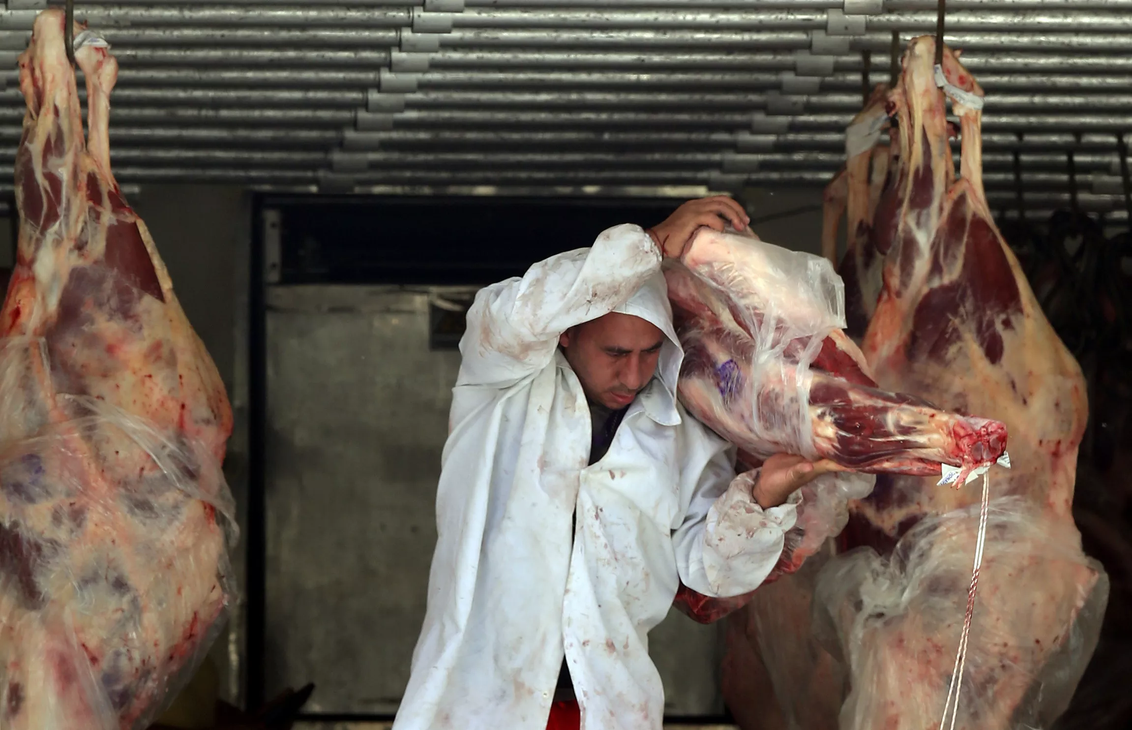 Açougueiro descarrega carne de um caminhão do lado de fora de um açougue 