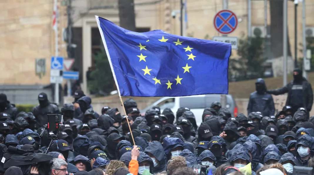 Um manifestante segura uma bandeira da União Europeia diante de policiais durante uma manifestação contra um projeto de lei sobre “agentes estrangeiros” em Tbilisi, Geórgia, em 14 de maio de 2024