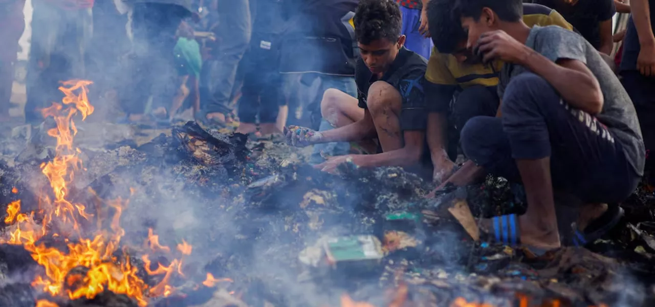 Palestinos procuram alimentos entre escombros após ataque israelense a um campo de refugiados em Rafah, na Faixa de Gaza