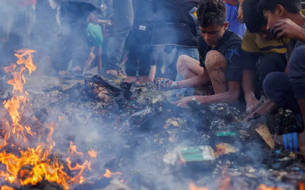 Palestinos procuram alimentos entre escombros após ataque israelense a um campo de refugiados em Rafah, na Faixa de Gaza