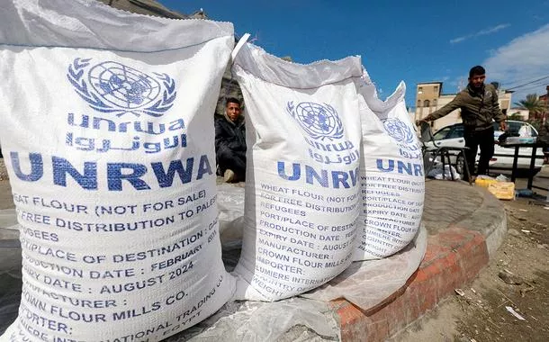 Palestinos deslocados esperam ajuda da Agência de Assistência e Obras das Nações Unidas (UNRWA), em Rafah, no sul da Faixa de Gaza