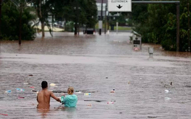 Pessoas tentam passar por área alagada em Encantado, no Rio Grande do Sul