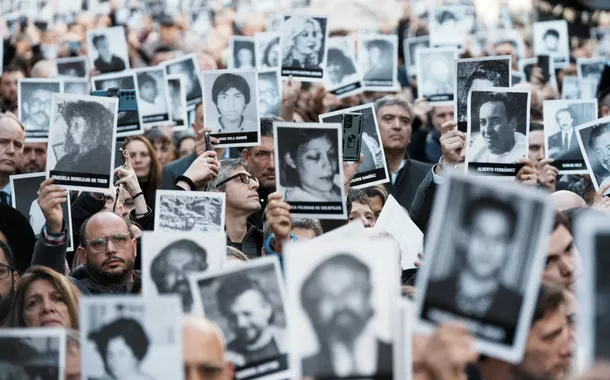 Pessoas seguram imagens das vítimas do ataque a bomba de 1994 no centro comunitário da Associação Mútua Israelita Argentina (AMIA), marcando o 30º aniversário do ataque, em Buenos Aires, Argentina, 18 de julho de 2024