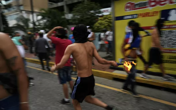 Um manifestante corre com um coquetel molotov em ação de vandalismo contra a decisão do povo. Caracas, Venezuela, 29 de julho