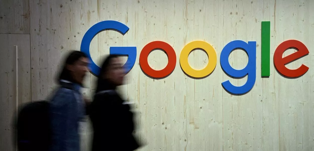 Pessoas passam em frente a logo do Google