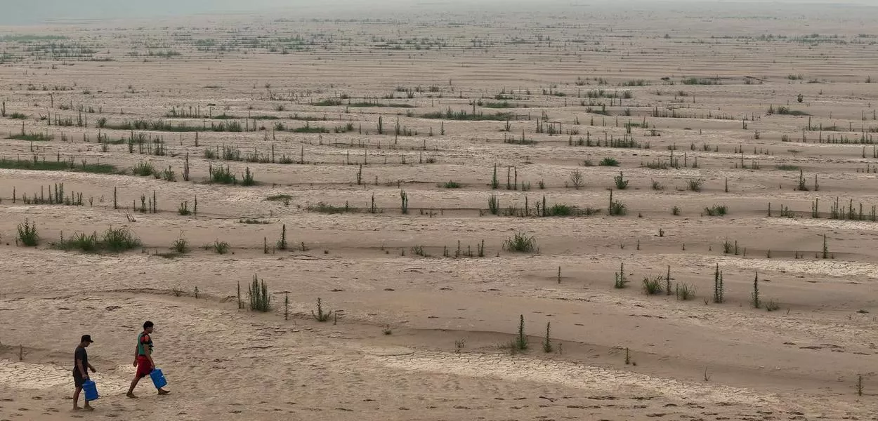 Ribeirinhos carregam galões de água enquanto atravessam bancos de areia do rio Madeira até a comunidade Paraizinho, em meio à pior seca da história. Humaitá, Amazonas. REUTERS/Bruno Kelly