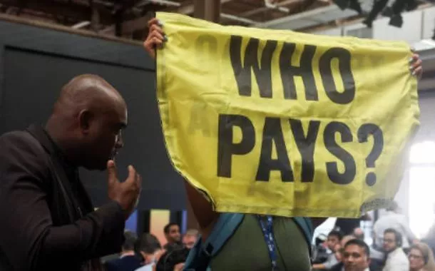 Ativista segura faixa com a frase 'Who pays?'