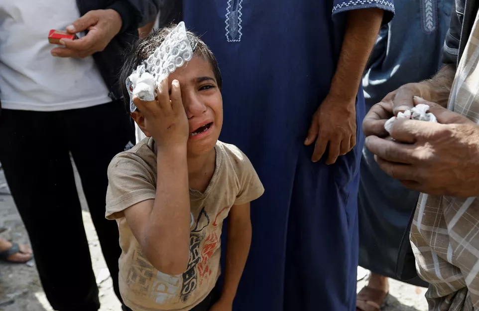 Um menino palestino reage no local dos ataques israelenses a casas, em Rafah, no sul da Faixa de Gaza, em 17 de outubro de 2023