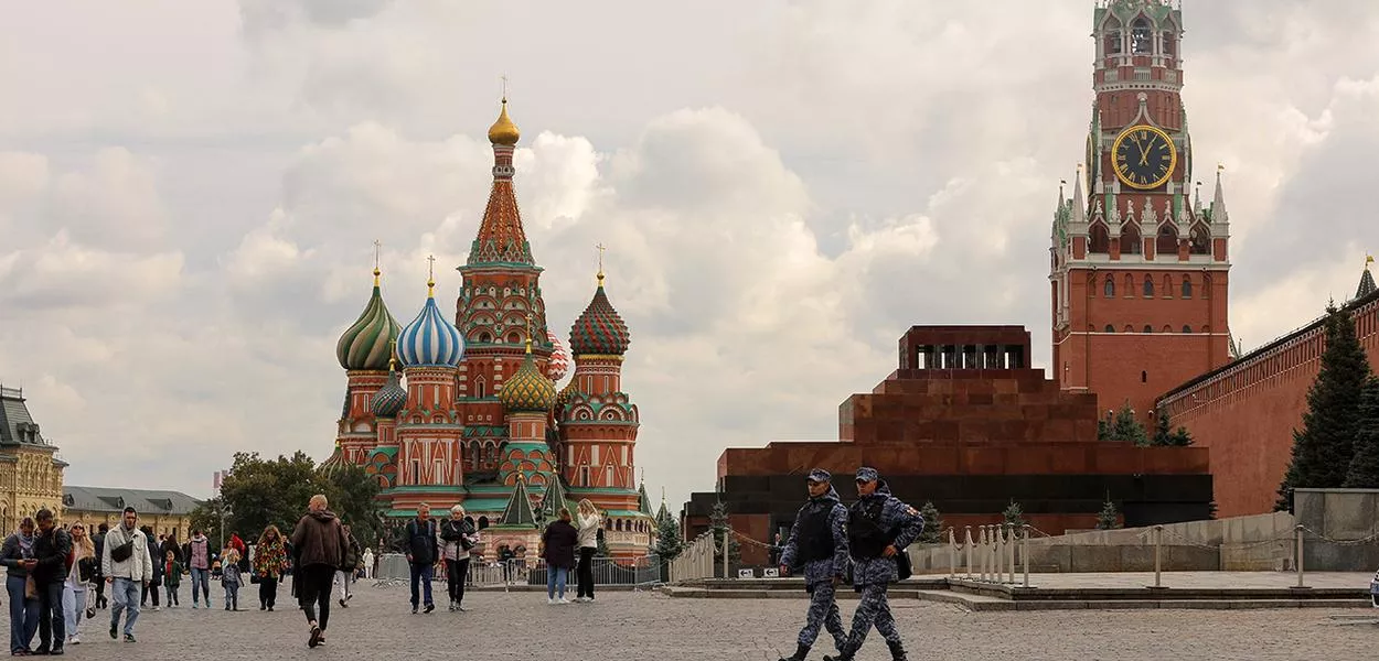 Pessoas atravessam a Praça Vermelha perto da Catedral de São Basílio e da Torre Spasskaya do Kremlin, no centro de Moscou, Rússia