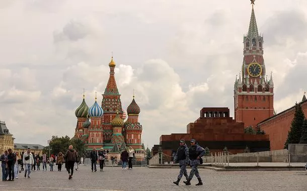 Pessoas atravessam a Praça Vermelha perto da Catedral de São Basílio e da Torre Spasskaya do Kremlin, no centro de Moscou, Rússia