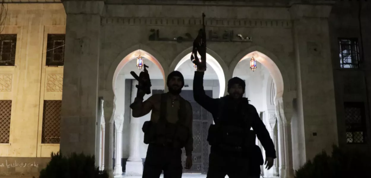 Terroristas seguram armas em frente ao prédio do governo de Hama