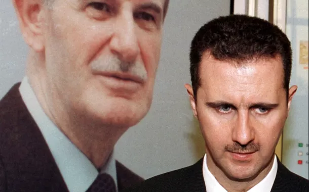 Bashar al-Assad ao lado da imagem do pai Hafez al-Assad