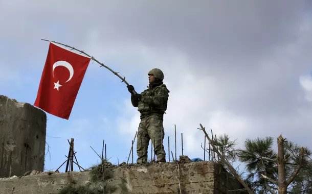 Um soldado turco agita uma bandeira no Monte Barsaya, a nordeste de Afrin, na Síria, em 28 de janeiro de 2018