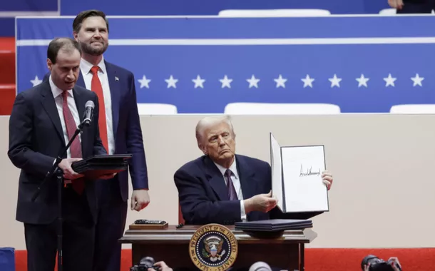 O presidente dos EUA, Donald Trump, mostra uma ordem executiva assinada enquanto o vice-presidente dos EUA, J.D. Vance, observa durante um comício no dia da posse de seu segundo mandato presidencial, dentro da Capital One, em Washington, EUA, 20 de janeiro de 2025