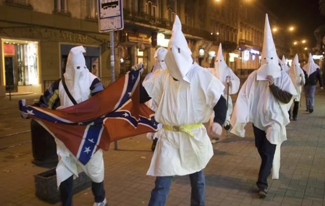 Apoiadores vestidos como membros da Ku Klux Klan, aproveitando a ocasião do Halloween para mascarar seus rostos da polícia, expressam opiniões antissemitas em Lviv, Ucrânia, 31 de outubro de 2009