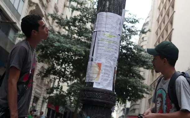 Jovens olham anúncios de vagas de emprego no centro de São Paulo