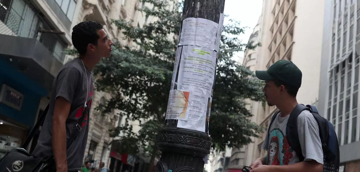 Jovens olham anúncios de vagas de emprego no centro de São Paulo