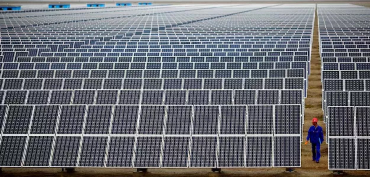Um trabalhador inspeciona painéis solares em uma fazenda solar em Dunhuang, 950 km a noroeste de Lanzhou, província de Gansu