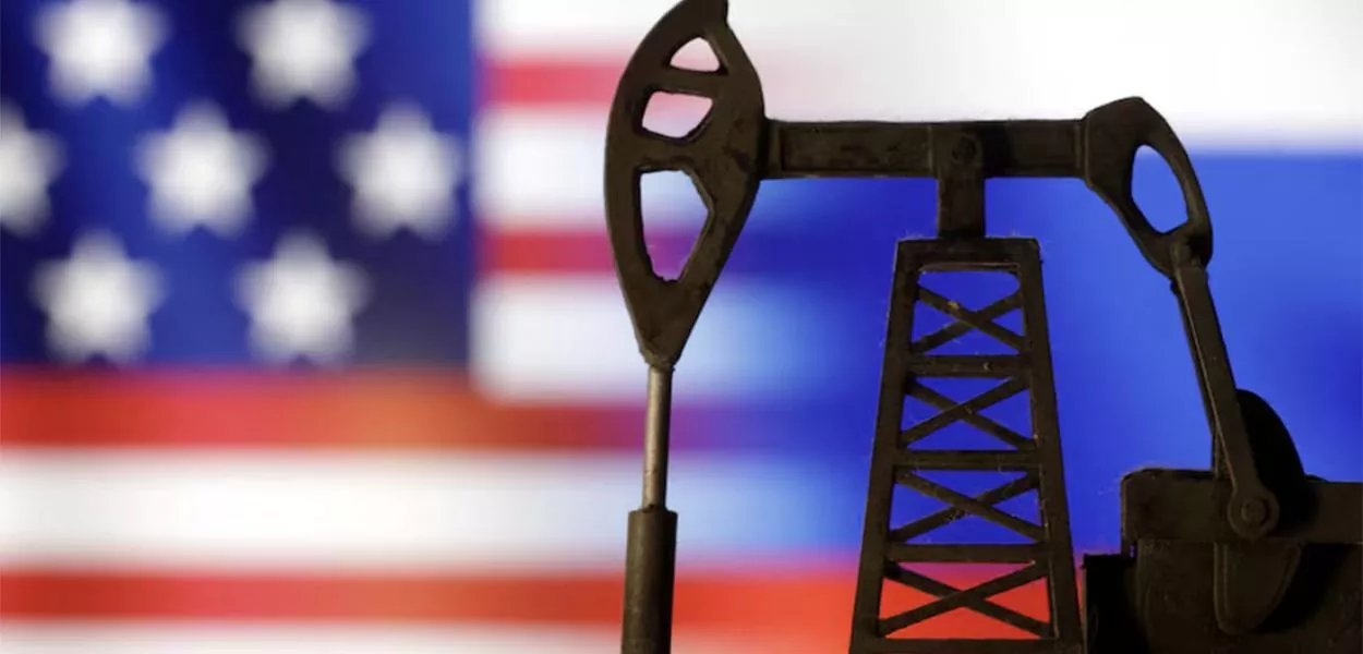 A model of an oil extraction pump is seen in front of the flags of the USA and Russia.