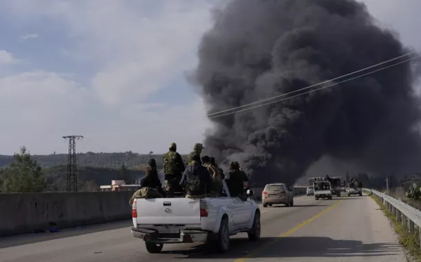 Fumaça sobe enquanto membros das novas forças regulares sírias viajam em um veículo enquanto lutam contra uma insurgência incipiente de combatentes aliados ao líder deposto Bashar al-Assad, em Latakia, Síria, 7 de março de 2025