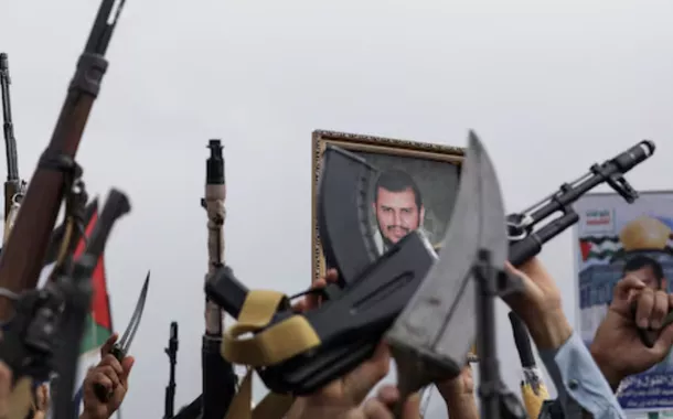 Um cartaz do líder Houthi, Abdul Malik al-Houthi, é segurado por um manifestante enquanto outros seguram suas armas durante uma manifestação em apoio aos palestinos na Faixa de Gaza, em Sanaa, Iêmen, em 26 de julho de 2024