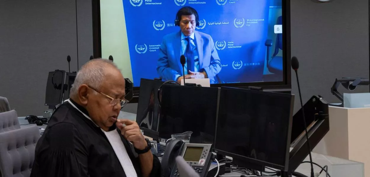 Ex-presidente filipino Rodrigo Duterte é visto em uma tela no TPI com seu advogado Salvador Medialdea sentado à esquerda