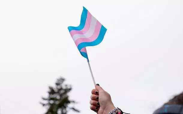 Manifestante segura bandeira trans durante ato em apoio a jovens trans