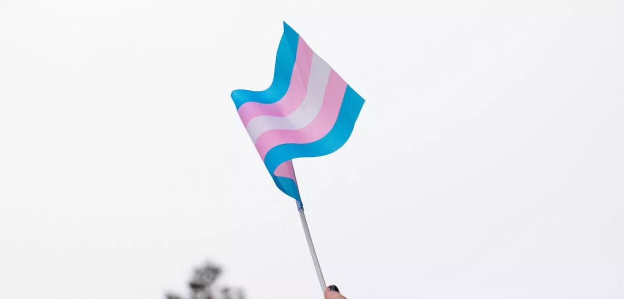 Manifestante segura bandeira trans durante ato em apoio a jovens trans