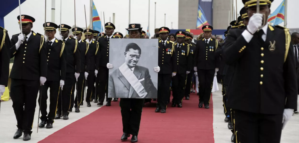 Membro da guarda de honra carrega um cartaz do herói da independência congolesa, Patrice Lumumba, durante sua cerimônia de sepultamento após seus restos mortais terem sido devolvidos à sua família pelo governo belga em Kinshasa, 30 de junho de 2022