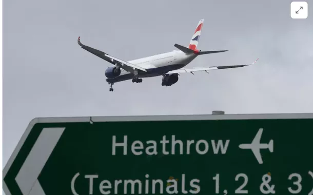 Um avião de passageiros da British Airways sobrevoa uma placa de sinalização rodoviária enquanto faz sua aproximação para pouso no Aeroporto de Heathrow, no oeste de Londres, Grã-Bretanha