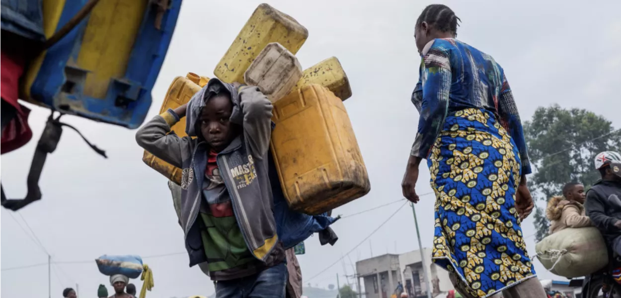 Civis deslocados internamente dos campos de Munigi e Kibati transportam os seus pertences enquanto fogem na sequência da luta entre os rebeldes M23 e as Forças Armadas da República Democrática do Congo (FARDC), em Goma, leste da República Democrática do Congo