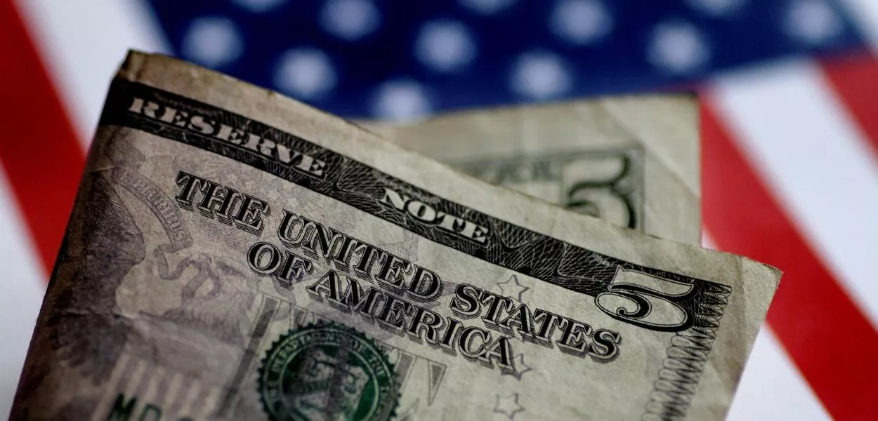 Nota de dólar aparece na frente de uma ilustração da bandeira dos EUA