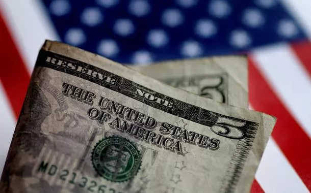 Nota de dólar aparece na frente de uma ilustração da bandeira dos EUA