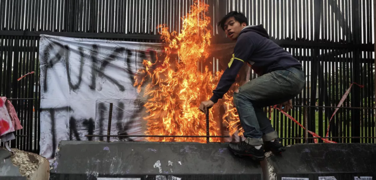 Homem em uma barreira de concreto durante um protesto em frente ao Parlamento indonésio, contra as revisões da lei militar do país, em Jacarta, Indonésia, 20 de março de 2025