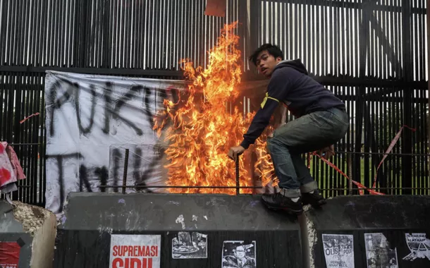 Homem em uma barreira de concreto durante um protesto em frente ao Parlamento indonésio, contra as revisões da lei militar do país, em Jacarta, Indonésia, 20 de março de 2025