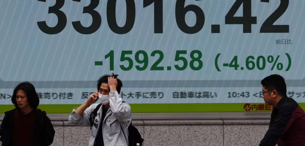 Pessoas passam por uma tela eletrônica exibindo a média das ações Nikkei do Japão do lado de fora de uma corretora em Tóquio, Japão, em 11 de abril de 2025. REUTERS/Kim Kyung-Hoon