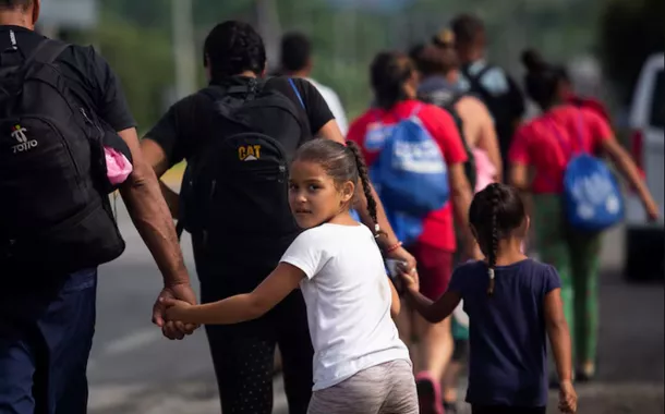 Crianças dão as mãos aos pais enquanto caminham com outros migrantes em uma caravana para cruzar o país e chegar à fronteira com os EUA, enquanto líderes regionais se reúnem em Los Angeles para discutir migração e outras questões, em Huixtla, México, em 7 de junho de 2022.