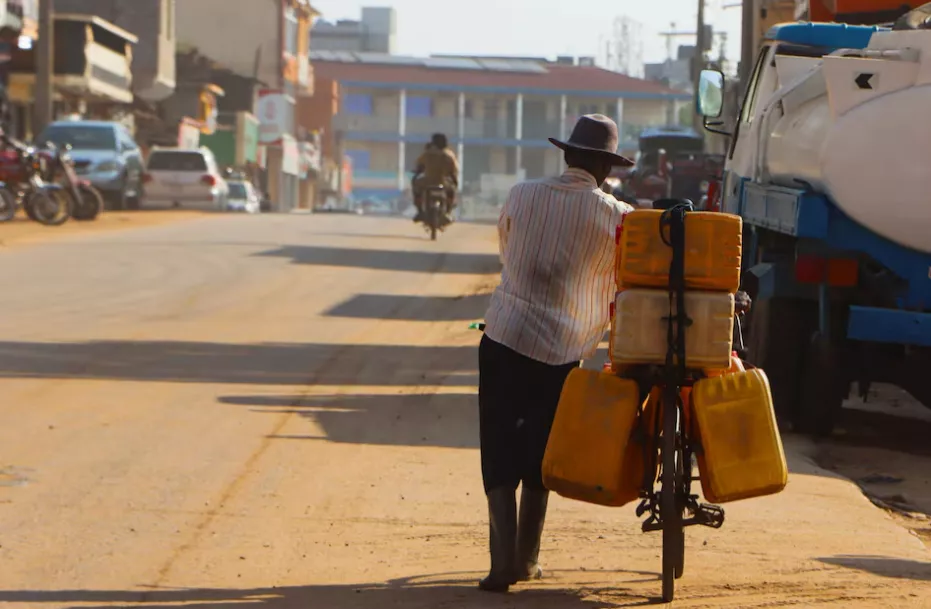 Um homem empurra sua bicicleta com galões de combustível por uma rua em Juba, Sudão do Sul, em 27 de março de 2025.