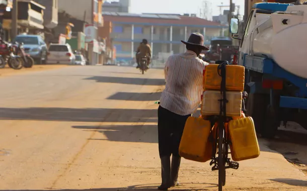 Um homem empurra sua bicicleta com galões de combustível por uma rua em Juba, Sudão do Sul, em 27 de março de 2025.