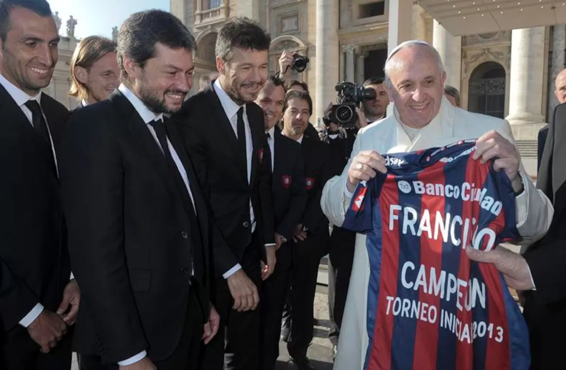 O Papa Francisco segura uma camisa do time de futebol argentino San Lorenzo, presenteada a ele por membros do time, durante a audiência geral de quarta-feira na Praça de São Pedro, no Vaticano - 18 de dezembro de 2013.