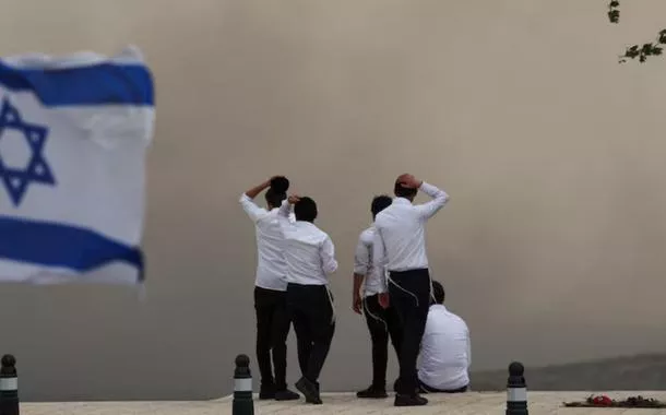 Pessoas observam a fumaça em Neve Ilan, enquanto incêndios florestais causados por calor extremo e ventos fortes irrompem no centro de Israel