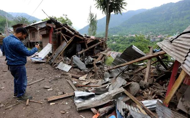 Um homem usa seu celular para filmar destroços de lojas danificadas por bombardeios transfronteiriços na vila de Lagama, perto da Linha de Controle (LoC) entre a Índia e o Paquistão, no distrito de Baramulla, na Caxemira indiana, em 9 de maio de 2025
