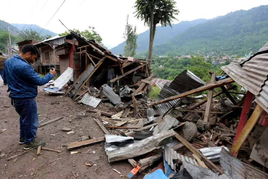 Um homem usa seu celular para filmar destroços de lojas danificadas por bombardeios transfronteiriços na vila de Lagama, perto da Linha de Controle (LoC) entre a Índia e o Paquistão, no distrito de Baramulla, na Caxemira indiana, em 9 de maio de 2025