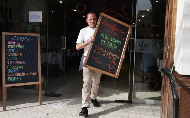 Homem segura quadro que diz: "O Papa comeu aqui. Comida abençoada, comida com fé", do lado de fora do restaurante "Las Américas", em Chiclayo - 09/05/2025