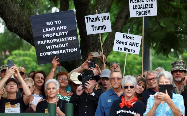 Manifestantes seguram cartazes em apoio à posição do presidente dos EUA, Donald Trump, contra o que ele chama de leis racistas, expropriação de terras e ataques a fazendas, em frente à Embaixada Americana em Pretória, África do Sul, em 15 de fevereiro de 2025.
