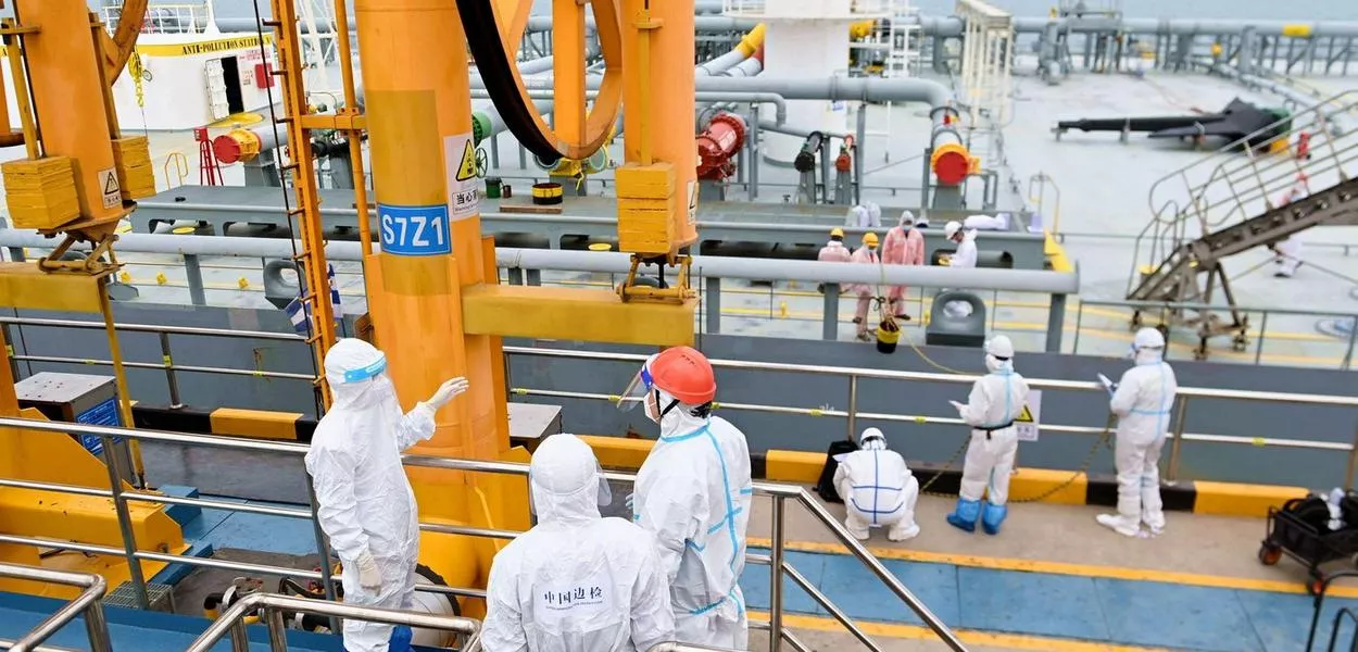 Oficiais de inspeção de imigração em trajes de proteção verificam um petroleiro transportando petróleo importado no porto de Qingdao, província de Shandong, China

