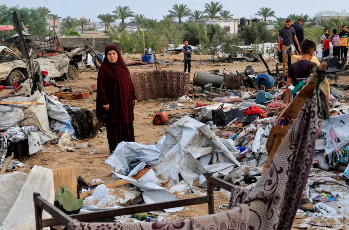 Palestinos inspecionam os danos no local de um ataque israelense a um acampamento de tendas que abrigava pessoas deslocadas, em Khan Younis, no sul da Faixa de Gaza, em 18 de maio de 2025