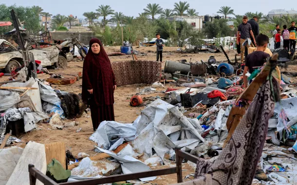 Palestinos inspecionam os danos no local de um ataque israelense a um acampamento de tendas que abrigava pessoas deslocadas, em Khan Younis, no sul da Faixa de Gaza, em 18 de maio de 2025