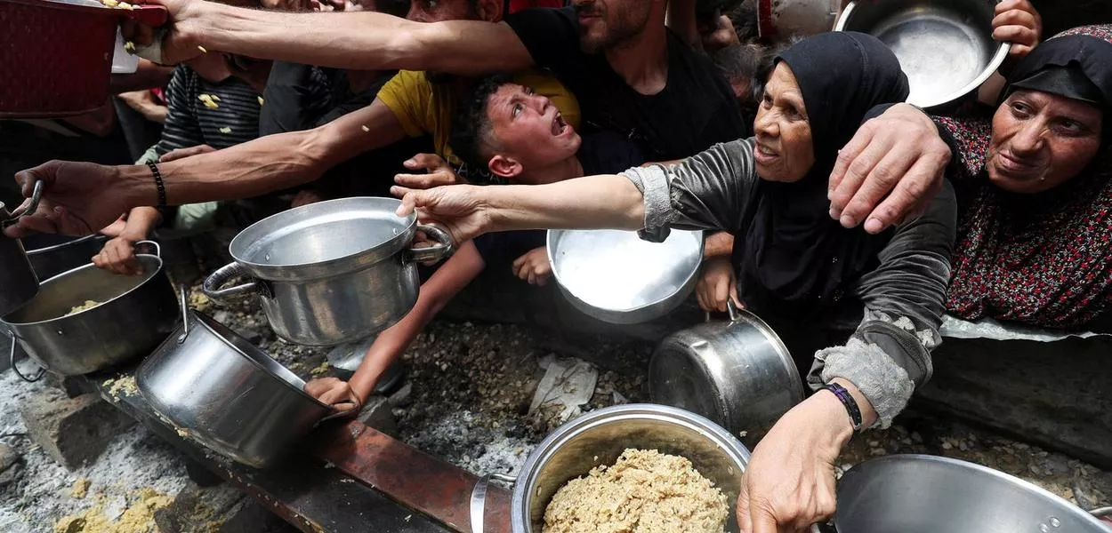 Palestinos recebendo comida em uma cozinha solidária no norte de Gaza
14/05/2025
